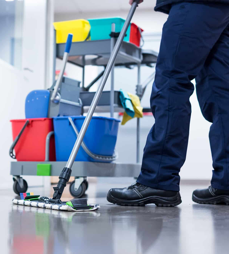 Professional cleaner carrying a cleaning caddy and broom inside a home